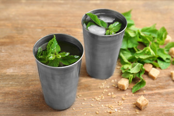 Two metal glasses with mint julep on wooden table