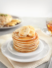 Plate with yummy banana pancakes on kitchen table