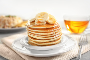 Plate with yummy banana pancakes on kitchen table