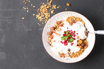 Granola with yoghurt, blueberries and blackberries in a white plate on a black background, selective focus, horizontal