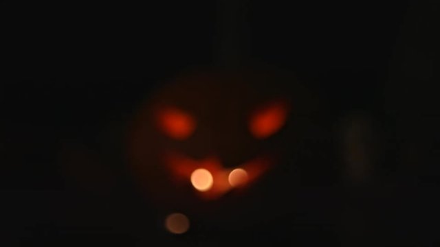 Carved Halloween pumpkin lights inside with flame and skuls around.