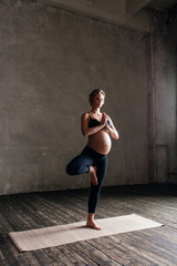 Fototapeta na wymiar Young beautiful pregnant yoga posing in studio
