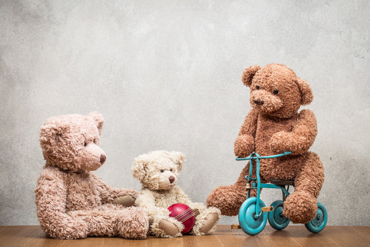 Retro Teddy Bear toys family: parents playing with child front concrete wall background. Parenthood concept. Vintage old style filtered photo