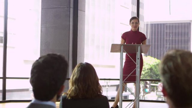 Young woman at a lectern presenting a business seminar, shot on R3D