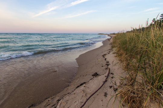 Sandy Beach Sunset Background. Wide sandy beach with surf on the shore of Lake Huron and sunset horizon in the background. Color image in horizontal orientation with copy space in the foreground.