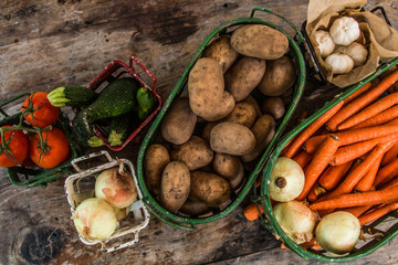 Vegetables in metal baskets on distressed vintage wood background 