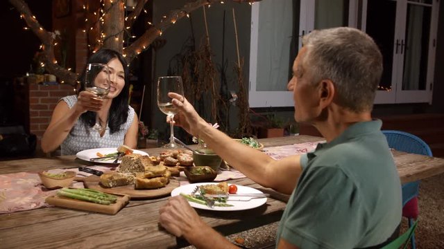 Mature Couple Enjoying Outdoor Meal In Backyard