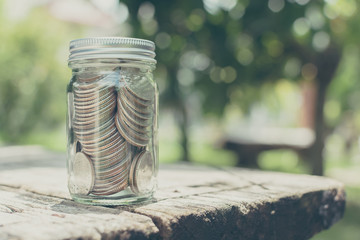 Coin in bottle glass on wood table with blurred green garden background, Copy space