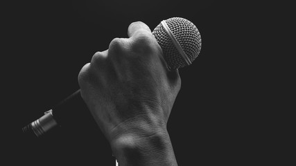 Man hands holding microphone on stand. - obrazy, fototapety, plakaty