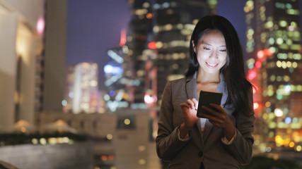 Business woman using cellphone in city at night