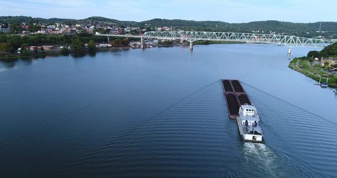 A high wide angle aerial establishing shot of a coal barge traveling on the Ohio River in Western Pennsylvania.  	