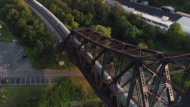 A dynamic forward moving aerial establishing shot of a cargo trail traveling on a railroad bridge over the Ohio River in Western Pennsylvania.  	