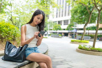 Fototapeta premium Business woman use of mobile phone and sitting outside