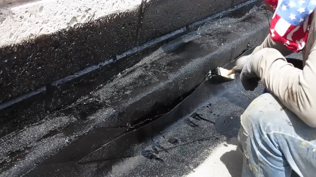 Roofer deals bitumen mastic on the roof