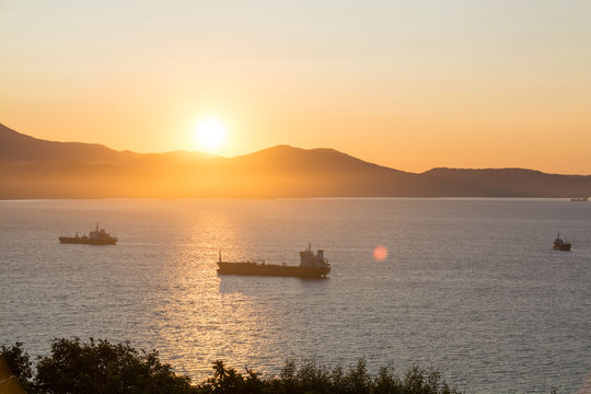 Commercial ships anchored at the bay with golden sunrise in the morning.