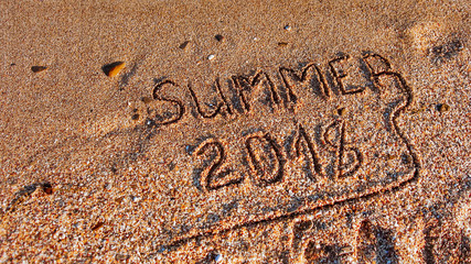 Fototapeta premium Summer 2018 written on the sea beach.Textured sandy template for New year greetings
