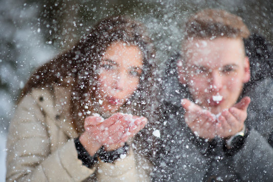 Young couple in love blowing snow away
