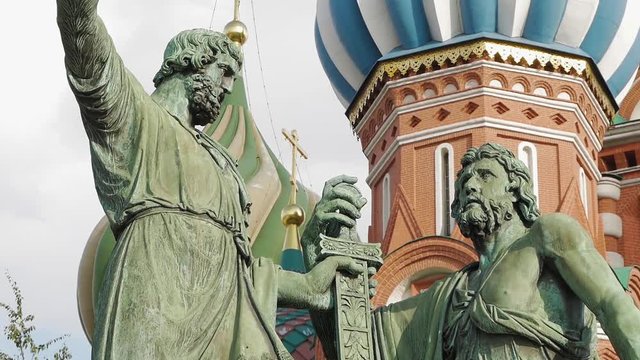 Close up shot of Minin and Pozharsky monument in front of colorful domes and other fragments of St Basil's Cathedral on Red Square near Kremlin. It's the major landmark in Moscow, Russia.
