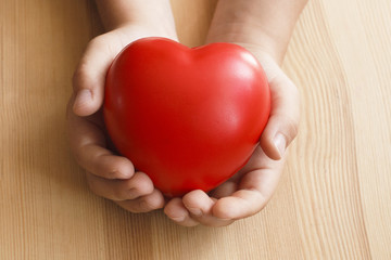 Heart in hand on wooden background