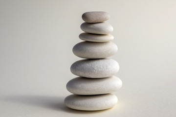 Fototapeta na wymiar Harmony and balance, cairns, simple poise stones on white background, rock zen sculpture, white pebbles, single tower, simplicit