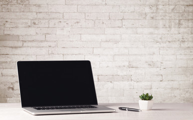 Business laptop with white brick wall