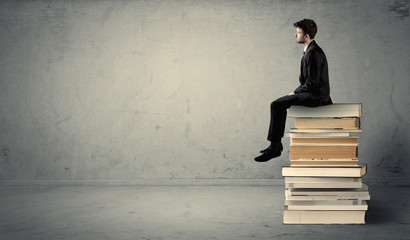 Student sitting on stack of books