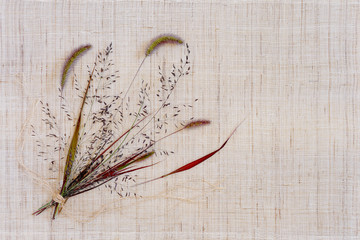 Small bouquet of autumn grasses on cloth napkin.
