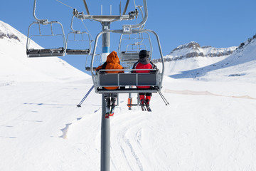 Two skiers on chair-lift and snow ski slope