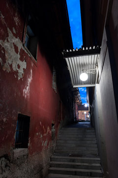 Narrow spooky street at night red scruffy wall claustrophobic skewed 