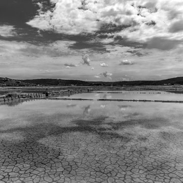 Old salt farm in Piran Slovenia sky and clouds are reflecting in the still water  black and white panorama 