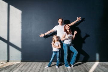 Fototapeta na wymiar Happy family portrait standing on gray background wooden floor room window sunny day