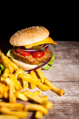 Delicious hommade tasty burgers on black and wooden background. Fast and tasty food