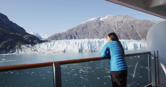 Alaska cruise ship passenger on balcony looking at glacier in Glacier Bay National Park, USA. Woman on travel vacation sailing enjoying view of Margerie Glacier. RED EPIC SLOW MOTION.