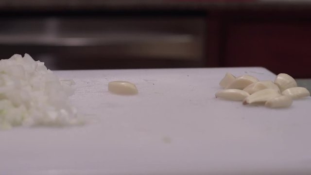 Cloves on garlic on cutting board with minced onions, close up