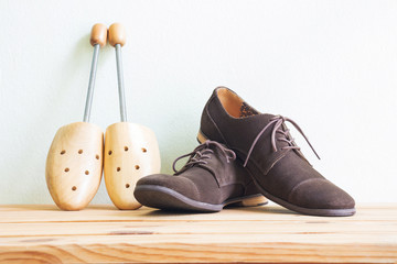 Men's accessories, vintage shoes and wooden shoe tree on wooden table over white wall background