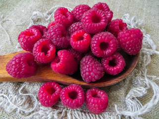 large fresh red raspberry berries, poured into a wooden spoon.