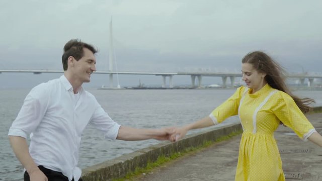 Emotional girl and boy dance jive on a pier with yachts in the background