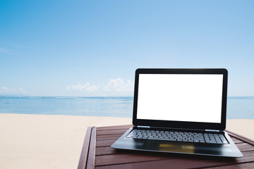 Laptop computer blank white screen on wood table at the beach. Clipping path on laptop screen