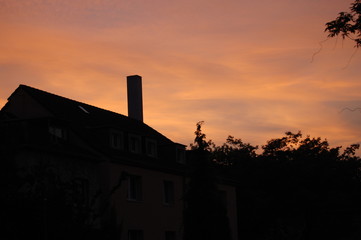 orangfarbener Abendhimmel über einem Haus