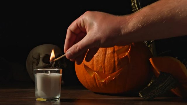 Carved Halloween pumpkin lights inside with flame and skuls around.