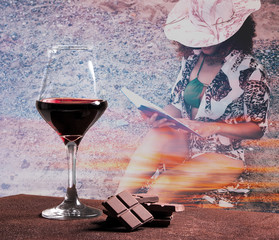 Red wine glass with chocolate and woman portrait reading book with sunset cloudscape