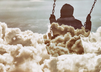 Double exposure of kid on swing and beautiful cloudscape