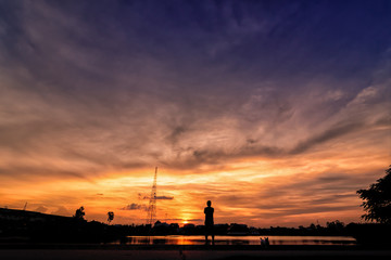 Fototapeta premium Silhouette backside of a man standing outdoors at sunset in the public park. 22-09-2017, Udonthani ,Thailand