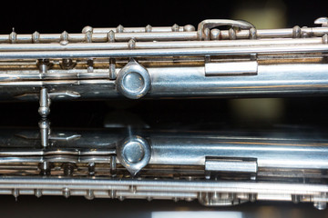 Obraz premium symphonic music concept - closeup on western concert flute body lies on the pure mirror black and white surface, middle section of wind instrument, studing and orchestra concerts usage, macro