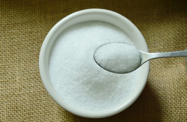 white cane sugar scooping on spoon over cup