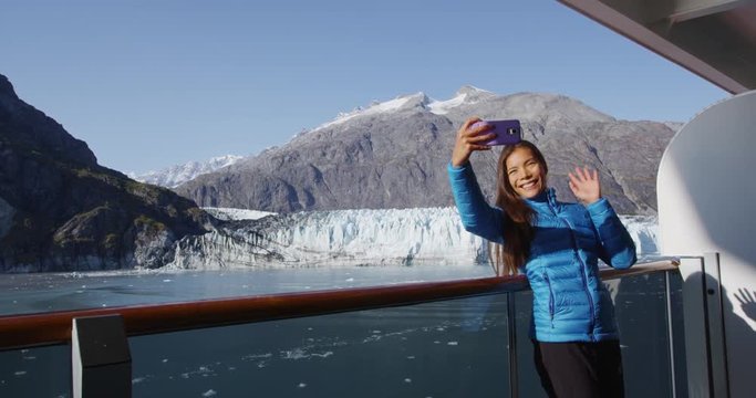 Tourist on Alaska cruise ship passenger taking selfie video or having video chat conversation in Glacier Bay National Park, USA. Woman tourist on smart phone on travel vacation.
