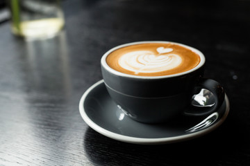 A cup of hot latte art or cappuccino coffee on wooden table
