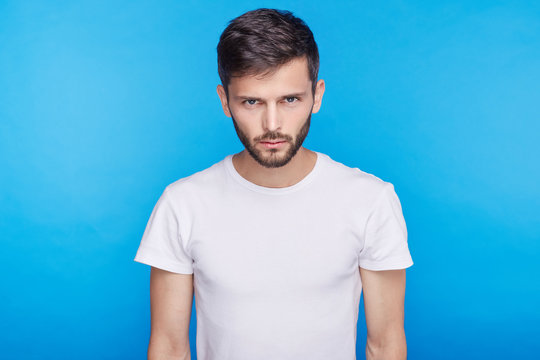Studio portrait of displeased, angry, grumpy Caucasian attractive male frowning at camera, pursing lips, having bad mood, feeling dissatisfied and furious with something, accusing or blaming.