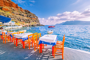 Outdoor restaurant at seashore on Greek resort island Santorini in Oia village.