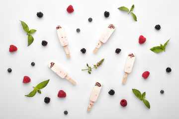Homemade yogurt ice cream popsicles with mint and berries on a white background, top view.